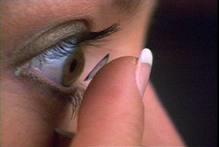 closeup side-view person placing contact lens to eye